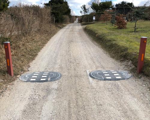 TDJ Vejbump 30 km/t Typegodkendt 2-delt 2 x 114 cm med pullert steler på grusvej. Trafikgummi.dk TDJ Vejbump 30 km/t Typegodkendt 2-delt 2 x 114 cm med pullert steler på grusvej.